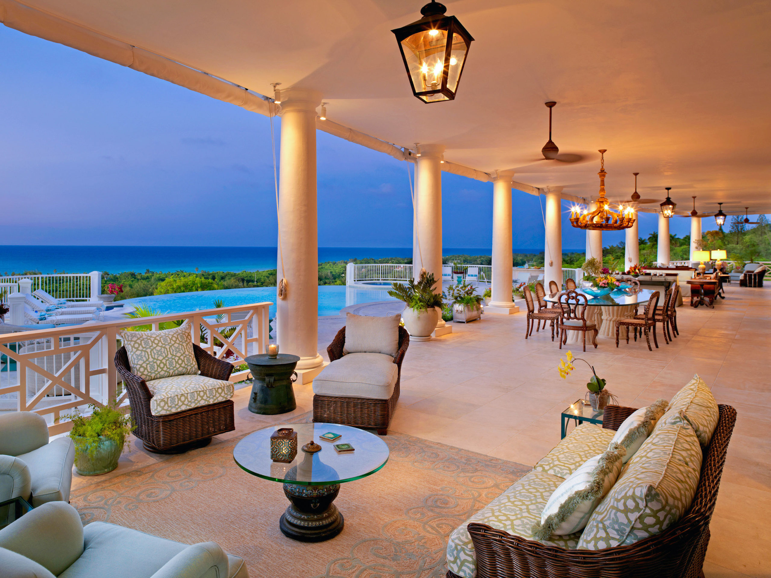 Stylish open-air patio with tables and chairs next to pool and ocean 