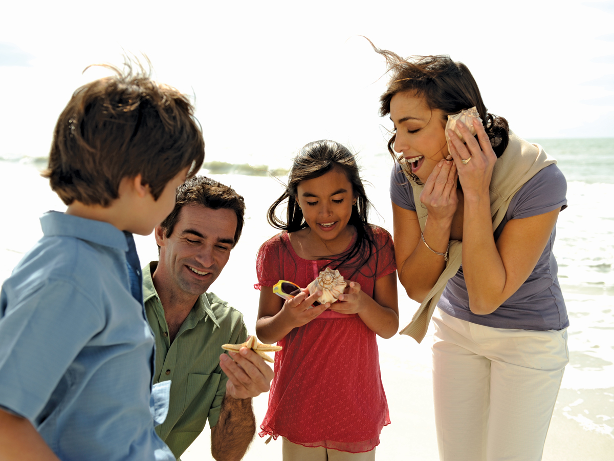 Family listening to shells on the beach