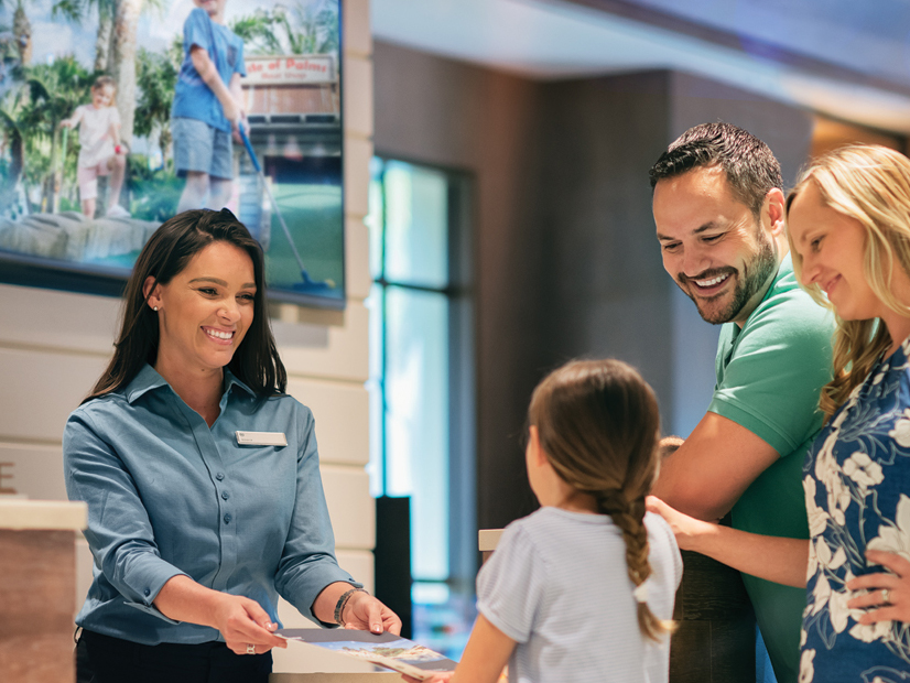 Friendly resort staff member helping happy family check in