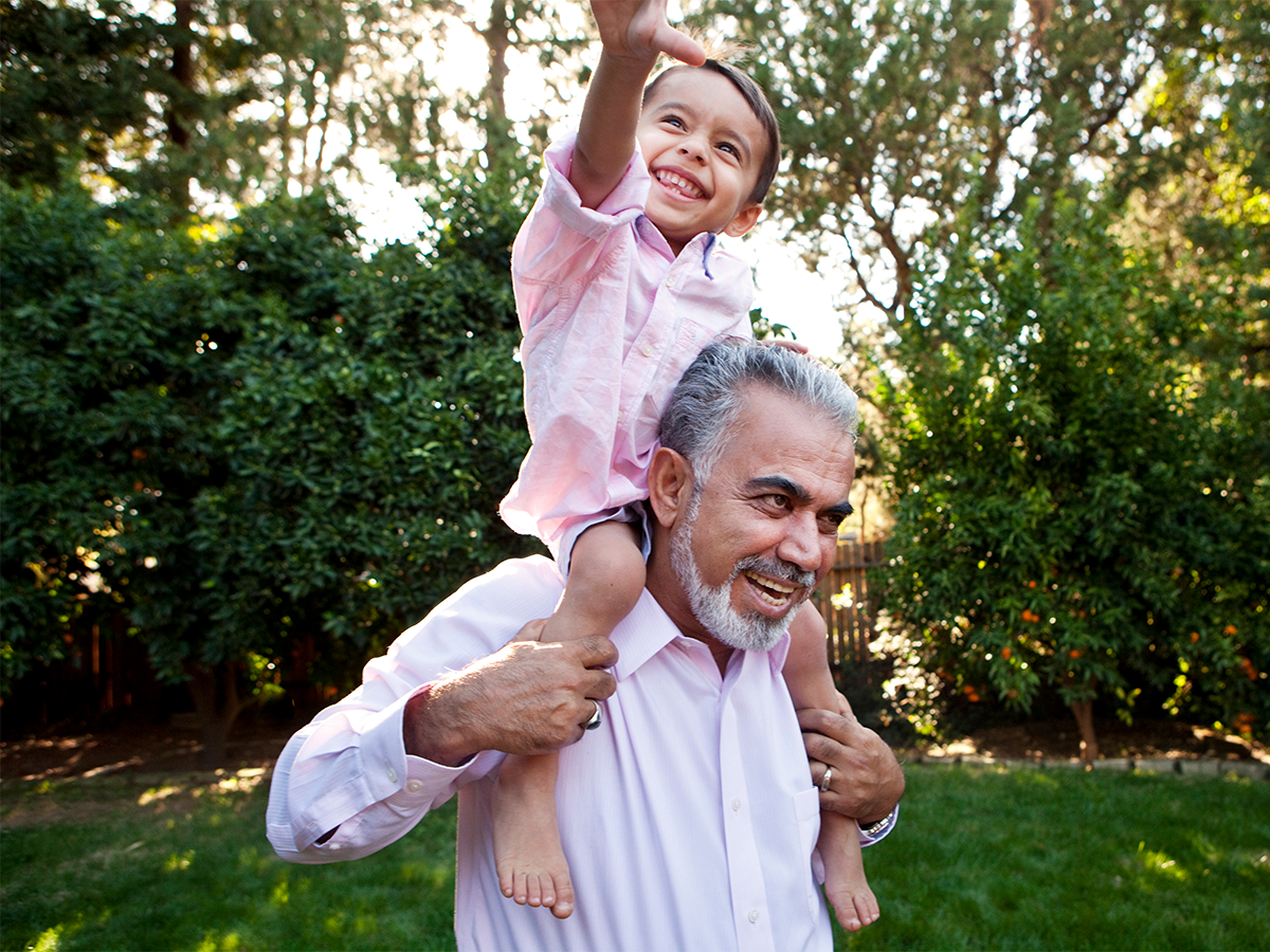 Grandfather with child on his shoulders enjoying the countryside